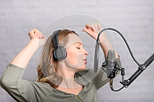 Female vocal recording. Young girl with microphone and headphones in recording studio. Recording of vocal, blogger, reading text,