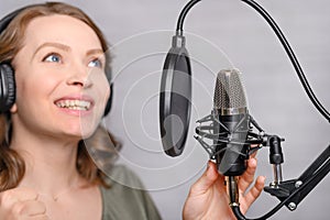 Female vocal recording. Young girl with microphone and headphones in recording studio. Recording of vocal, blogger, reading text,