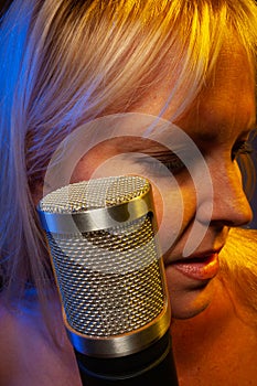 Female vocalist under gelled lighting with condenser microphone