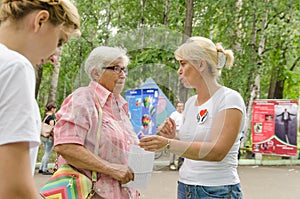 Female volunteer explains to elderly woman measurements of body fat measurement monitor and makes recommendations for healthy