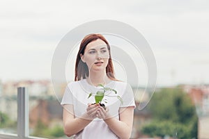Female volunteer holds in her hands a seedling of a flower tree