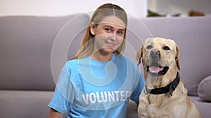 Female volunteer sitting near cute homeless labrador dog social adoption program