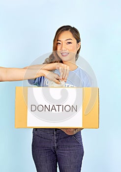 a female volunteer wears blue T-shirt holding donation box,woman hand giving banknote into donation box