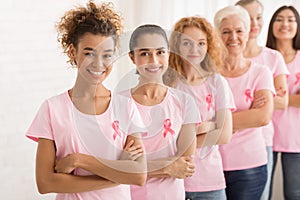 Female Volunteers In Breast Cancer T-Shirts Standing Over White Wall