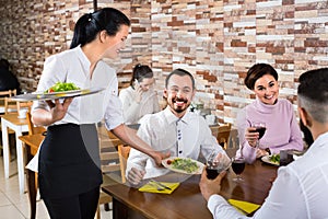 Female waiter bringing order to visitors in country restaurant