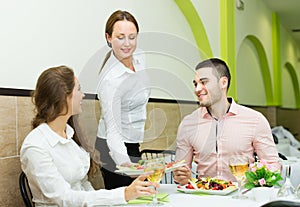 Female waiter serving guests table