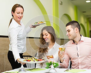 Female waiter serving guests table