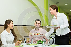 Female waiter serving guests table