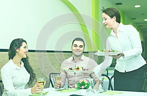 Female waiter serving guests table