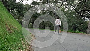 Female walking alone on a path in a park with tree all around, slow motion