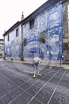 Female walking on the street in front of the building of Chapel Of Souls in Porto, Portugal