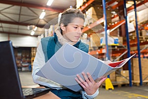 Female warehouse manager with file folder in warehouse photo