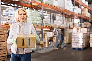 Female warehouse worker carrying cardboard boxes