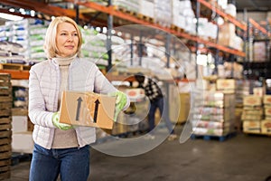 Female warehouse worker carrying cardboard boxes