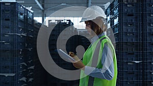 Female warehouse worker checking shipment boxes inspecting delivery package