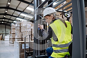 Female warehouse worker driving forklift. Warehouse worker preparing products for shipmennt, delivery, checking stock in