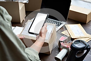 Female warehouse worker holding parcel box using mobile application. photo