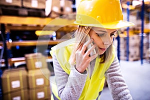 Female warehouse worker with smartphone.