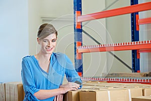 Female warehouse worker smiling smiling with boxes and packages indoors