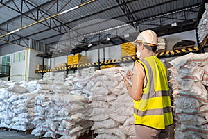 A Female warehouse worker is taking note of the number of chemicals in alum or chemical warehouse storage. International export