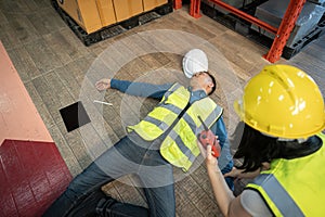 A female warehouse worker using a walkie-talkie called the factory's first aid team to rescue an unconscious man