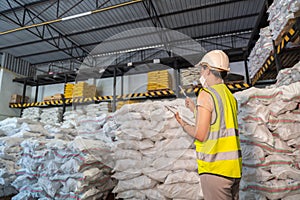 A Female warehouse worker wear a mask inspecting chemical products in alum or chemical warehouse storage. International export