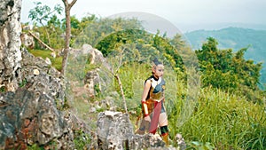 a female warrior in a golden dress and crown walks in a forest with a tired and haggard face