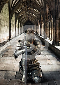 Female warrior knight kneeling proudly wearing decorative metal armor and holding a sword.