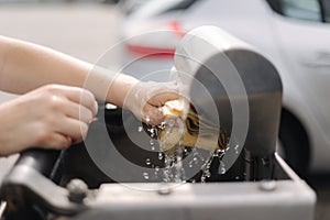 Female wash rug in water. Close-up woman& x27;s hand in front of car on self servise car wash. Squeez rug
