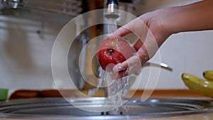 Female Washes Ripe, Red Apple with Stream Running Water from a Tap in Kitchen.