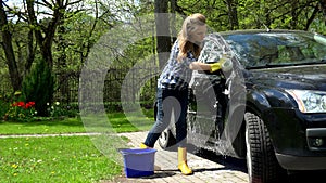 Female washing her car at house yard in garden.