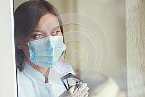 Female wearing protective mask at medical clinic. Woman hope faith in overcoming Coronavirus pandemic