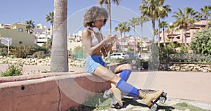 Female wearing rollerskates sitting on curb