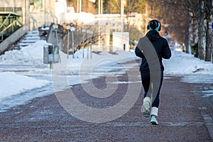 Female wearing a sweatsuit running on a snowy, frosty street