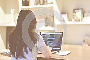 Female web developer writing code on laptop in co-working space as remote work.