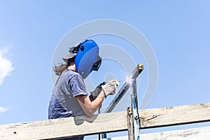 Female welder fixing fence