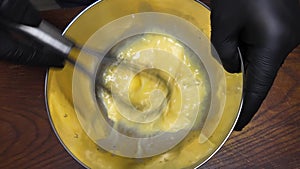 Female whisking chicken eggs in a metal bowl