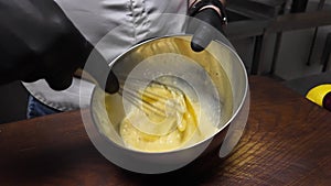 Female whisking chicken eggs in a metal bowl. Slow motion