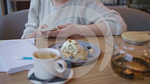 female white shirt working cafe while having lunch desert tea smartphone hands