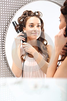 Female winds hair on the curling iron