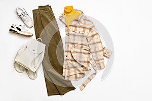 Female winter or autumn stylish clothing set. Plaid checkered shirt, yellow sweater, green corduroy trousers, sneakers and