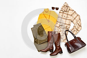 Female winter or autumn stylish clothing set. Plaid checkered shirt, yellow sweater and leather boots, green corduroy trousers,