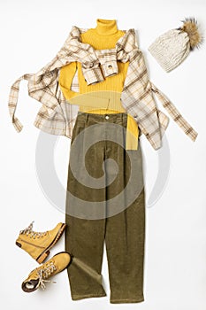 Female winter or autumn stylish clothing set. Plaid checkered shirt, yellow sweater and leather boots, green corduroy trousers,