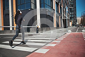 Female in wireless headphones working out in the city center