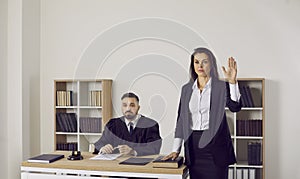 Female witness swears on the Bible before giving a testimony during the court trial