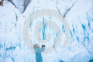 Female wonderer shooting video on smartphone of a big ice rock