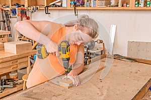 Female woodworker drilling into board