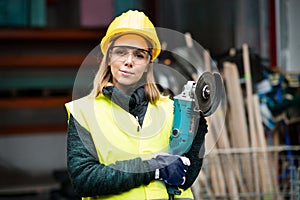 Female worker with angle grinder in a warehouse.