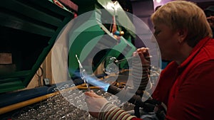 A female worker blows glass Christmas toys in a factory.