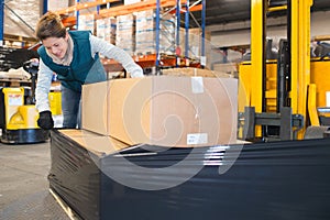 female worker checking shrink wrap on forklift load